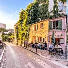 Ulica na Montmartre, z kawiarnią La Maison Rose i ludźmi siedzącymi przy stolikach.
