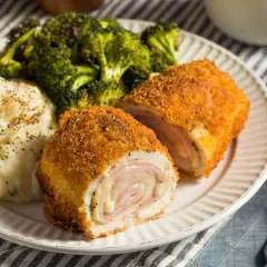 Un delicioso cordon bleu, crujiente por fuera y jugoso por dentro, acompañado de puré de patatas y brócoli.