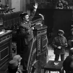 Un militar con pistola en mano, saludando, en el Congreso durante el golpe de estado de Tejero. Soldados armados observan.