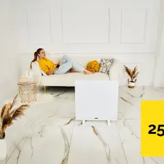 Kobieta relaksuje się na kanapie, podczas gdy panel grzewczy na podczerwień ogrzewa pomieszczenie 25 m².