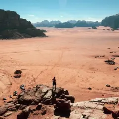 Pustynia Wadi Rum w Jordanii, gdzie turysta czeka na wizę, podziwia krajobraz z samotnym drzewem i samochodami terenowymi.