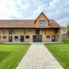 Belle grange rénovée avec une extension en bois. Le chemin pavé mène à la porte de garage. Le prix de la rénovation de grange est justifié par ce résultat.