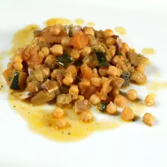 Deliciosos garbanzos con pisto, una mezcla colorida de verduras y legumbres en un plato blanco.