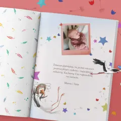 Gotowe dedykacje do książki: zdjęcie noworodka i bocian niosący dziecko. "Kochamy Cię najbardziej na świecie. Mama i Tata.