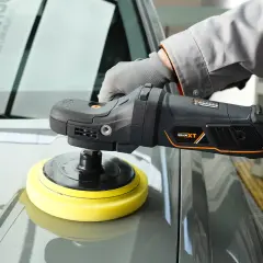 Persona con guantes usa una pulidora para detallar el capó de un coche gris.