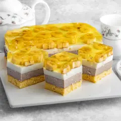 Pyszne bananowiec ciasto z galaretką i bananami, pokrojone na porcje. Obok czajniczek i filiżanka.
