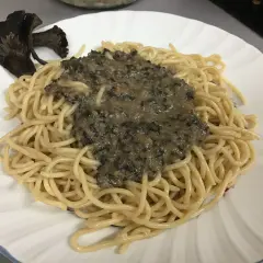 Deliciosa pasta con una cremosa salsa de trompetas de la muerte y un hongo entero como decoración.