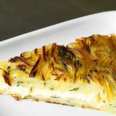 En gyllene potatiskaka i ugn med en krämig fyllning, serverad på en vit tallrik.