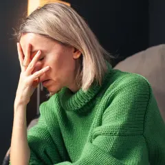 Donna con la mano sulla fronte, visibilmente provata. Un'immagine che evoca la lotta contro ansia e depressione, e la ricerca di come uscirne.
