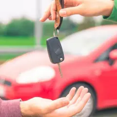 Passaggio di chiavi per vendere l'auto velocemente. Una mano porge le chiavi di un'auto rossa a un'altra mano.