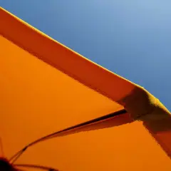 Orange Sonnenschirm-Stoff mit Baumwolle für UV-Schutz vor blauem Himmel.