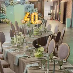 Eleganckie przyjęcie weselne na 40 osób. Stoły nakryte, ozdobione kwiatami i świecami. W tle dekoracje z balonów i podświetlana liczba 40.