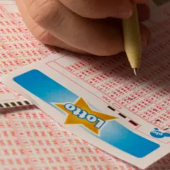 Dłoń zaznacza liczby na kuponie Lotto. Czy to będą zwycięskie lotto kaskada wyniki?