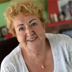 Uśmiechnięta Henryka Krzywoń Strycharska z blond włosami i złotym naszyjnikiem.