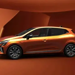 Pomarańczowy Renault Clio 6 z nowoczesnym designem, prezentowany na tle architektonicznych form w odcieniach brązu.