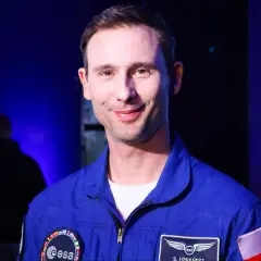 Uśmiechnięty polak w niebieskim kombinezonie ESA, gotowy na misję na Księżyc.