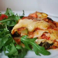 En bit krämig grönsakslasagne med ruccolasallad, perfekt för en vegetarisk recept topplista.
