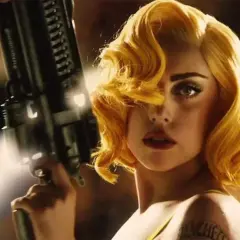 Lady Gaga med blont hår och en futuristisk pistol i en scen från en av hennes filmer.