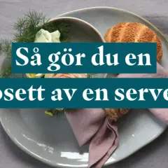 En dukning med en rosett av en servett, blommor och en bulle.