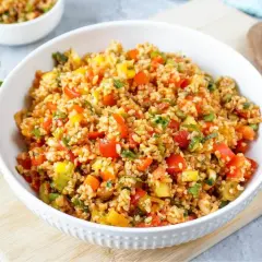Frischer bulgur salat mit bunten Paprikawürfeln und Kräutern, serviert in einer weißen Schüssel.