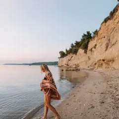 Mujer rubia camina por la playa, sintiendo la brisa marina. Ella anhela la libertad y el deseo de querer viajar sola.