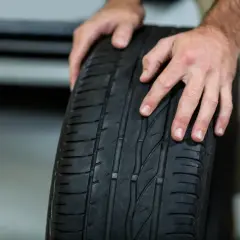 Manos revisando un neumático desgastado, preguntándose cada cuanto se cambian las ruedas para garantizar la seguridad.