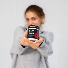 Młoda kobieta prezentuje krem do masażu rozgrzewający Line Sport. Idealny po treningu.