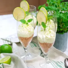 Söta key lime pie i glas, toppad med vispgrädde och lime. En perfekt dessert för sommaren.