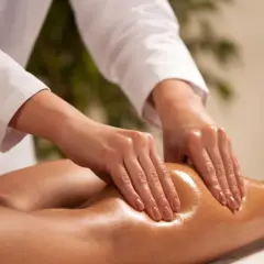 Dłonie terapeuty wykonują masaż łydki, przygotowując ją do zabiegu presoterapii.