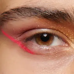 Occhio con eyeliner fucsia audace e ombretto dorato scintillante. Un look di trucchi per gli occhi che cattura l'attenzione.