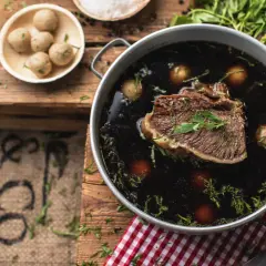 Ein köstliches Tafelspitz-Rezept: Zartes Rindfleisch in dunkler Brühe mit kleinen Klößchen und frischer Petersilie.