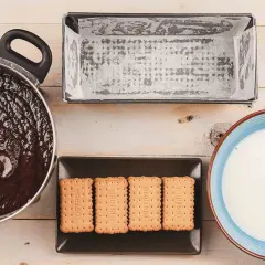 Preparando una deliciosa tarta de galletas y chocolate: chocolate derretido, galletas, molde y leche.