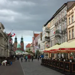 Spacer po Gnieźnie, gdzie widać zabytkowe kamienice, katedrę i ludzi odpoczywających w ogródku piwnym.