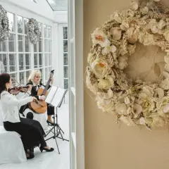 Dwie artystki tworzą oprawę muzyczną ślubu w kościele: jedna gra na skrzypcach, druga na gitarze.