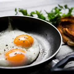 Deux œufs au plat parfaits dans une poêle, prêts à être dégustés. Une idée simple pour comment faire des oeufs au plat.