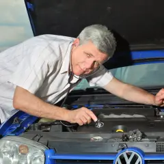 Mechanik zaintrygowany nasłuchuje silnika samochodu stetoskopem.