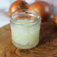 Zwiebelsaft husten: Gehackte Zwiebeln in einem Glas, bereit zur Zubereitung eines natürlichen Heilmittels gegen Husten.