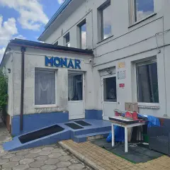 Budynek Monaru z niebieskim napisem, wejściem i otoczeniem.