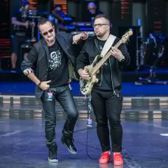 Dwóch muzyków na scenie, jeden z gitarą basową, drugi w okularach przeciwsłonecznych. Wyglądają jak nowy wokalista Kombi i jego kolega z zespołu.
