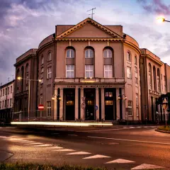 Teatr im. Adama Mickiewicza w Częstochowie nocą, z rozmazanymi światłami samochodów. Kto jest dyrektorem teatru w Częstochowie?