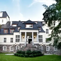 Elegancki pałac w Ciekocinku otoczony zielenią, z kamienną podstawą i kolumnowym wejściem.