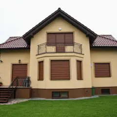 Dom z brązowymi roletami zewnętrznymi, gotowy na silny wiatr.