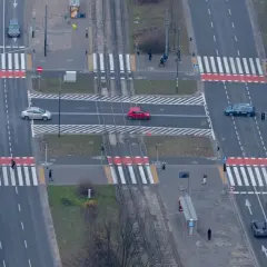 Skrzyżowanie z przejściami dla pieszych. Czerwony samochód jedzie po pasach, zastanawiając się, ile za wyprzedzanie na pasach.