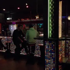 Leute sitzen an einer Bar in Stuttgart, die mit bunten Lichtern beleuchtet ist. Ein gemütlicher Abend im Oblomow.