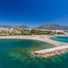 Piękne plaże i turkusowe morze w Puerto Banús, z górami w tle.