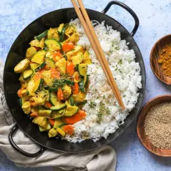 Ein leckeres Curry Geschnetzeltes Rezept mit Reis, Zucchini und Karotten, garniert mit Sesam und Kräutern.