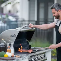 Mężczyzna w fartuchu grilluje łososia na grillu gazowym, pokazując, jak działa grill gazowy.