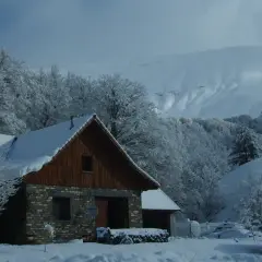 El refugio de Linza, cubierto de nieve, se alza entre árboles nevados y montañas imponentes.
