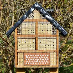 Ein Insektenhotel mit verschiedenen Fächern für Nützlinge, ideal als Standort im Garten.