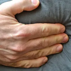 Eine Hand drückt auf den Bauch, was auf Beschwerden wie bei einer Lebensmittelunverträglichkeit hindeuten könnte.